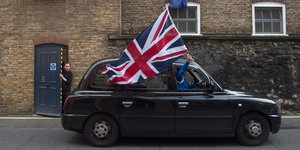 eine englische Fahne wird aus einem fahrenden Taxi gehalten