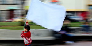 Ein Junge rennt mit einer mit weißen Fahne