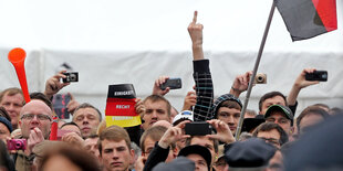 Ein Pegida-Demonstrant in der Menge zeigt den Stinkefinger