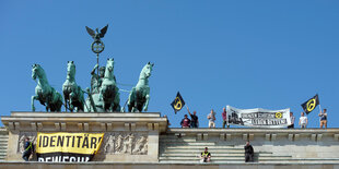 Männer protestieren mit Fahnen, auf denen "identitäre Bewegung", auf dem Brandenburger Tor