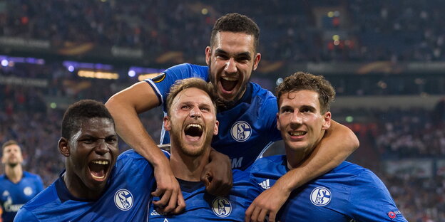 vier feiernde Fußballer in blauen Trikots