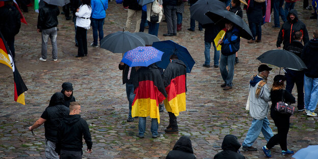Menschen mit Deutschlandfahnen und Regenschirmen
