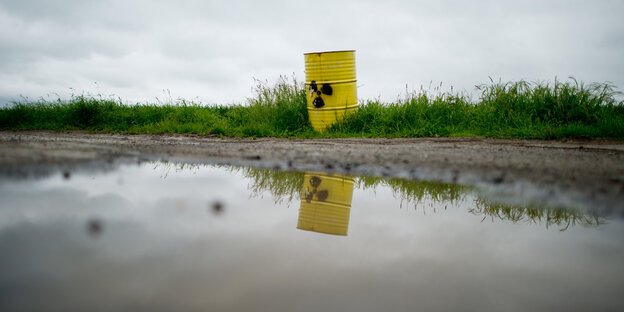 ein einzelnes gelbes Fass mit offenbar radioaktivem Müll steht an einer Pfütze