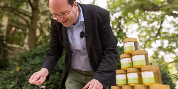 Niedersachsens Landwirtschaftsminister Christian Meyer lässt flüssigen Honig von einem Löffel tropfen.