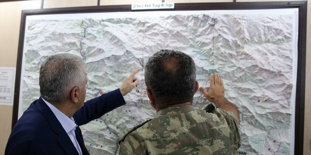 Binali Yildirim und ein Kommandeur stehen vor einer Karte, die an der Wand hängt
