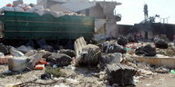 Ein zerstörter Lastwagen liegt auf einer staubigen Ebene, ringsum liegen Gegenstände verstreut