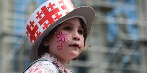 Mädchen trägt einen Hut mit dem georgischen Wappenmuster