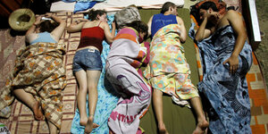 Fünf Jugendlche schlafen auf Isomatten unter bunten Decken