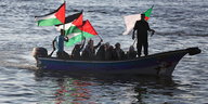 Palästinensische Frauen in einem Boot schwenken Flaggen und machen das Victory-Zeichen