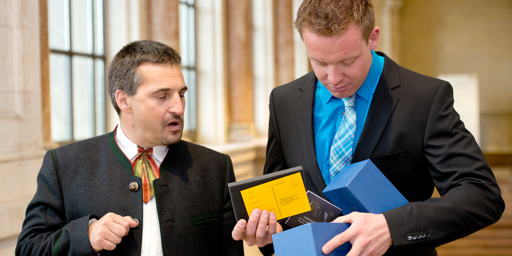 Felix Loch und Georg Hackl packen ein Geschenk aus