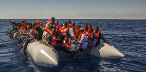 Flüchtlinge aus Somalia und Eritrea sitzen mit Rettungswesten in einem Boot