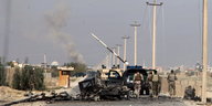 Ausgebranntes Auto auf einer Straße mit Soldaten