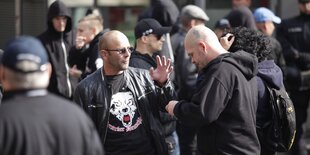 Ein Mann steht auf einer Demonstration mit einem T-Shirt, auf dem ein Wolf abgebildet ist und in Frakturschrift: "Berseker Deutschland" steht.