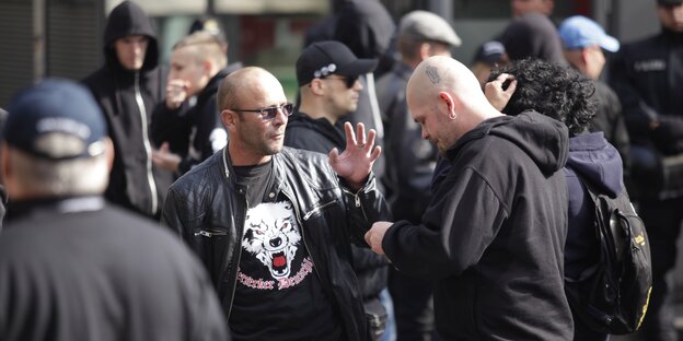 Ein Mann steht auf einer Demonstration mit einem T-Shirt, auf dem ein Wolf abgebildet ist und in Frakturschrift: "Berseker Deutschland" steht.