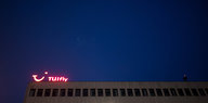 Rot leuchtendes Tuifly-Logo auf einem mehrstöckigen Haus bei Nacht