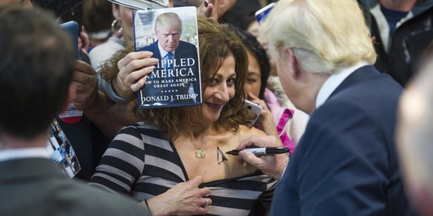 Donald Trump signiert einer Frau den Ausschnitt