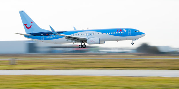 Eine blaue Boeing 737-800 von Tuifly überfliegt eine Landebahn
