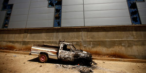Ein ausgebranntes Fahrzeug steht vor einer Mauer