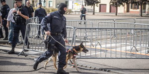 Vor einer Absperrung sind Polizisten zu sehen, einer mit einem Polizeihund