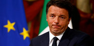Matteo Renzi mit zusammengepressten Lippen vor einer EU- und einer Italienflagge