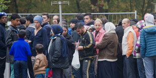 Menschen warten vor einem Zaum