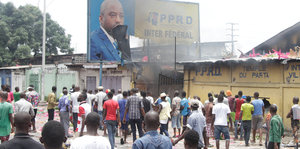 Unterstützer der Opposition protestieren und zerstören ein Plakat von Präsident Kabila.