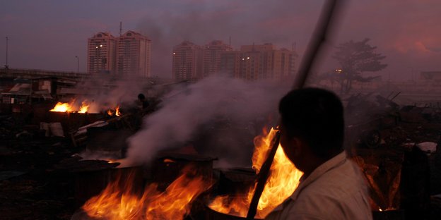 Ein indonesischer Arbeiter verbrennt Kokosnussschalen im Slum von Jakarta