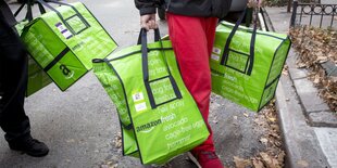 Zwei Menschen tragen neon-grüne Taschen von Amazon