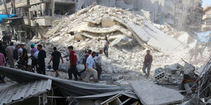 Menschen laufen in den Trümmern von Aleppo