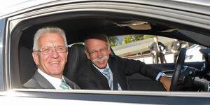 Winfried Kretschmann sitzt mit Dieter Zetsche in einem Auto. Sie lächeln