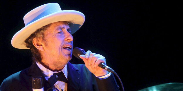 Bob Dylan mit Hut und Mikro auf der Bühne