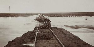 Ein Mann sitzt auf einer Eisenbahnschiene