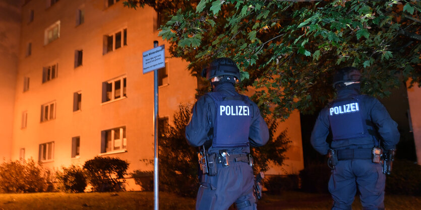 Polizisten stehen vor einem Wohnhaus