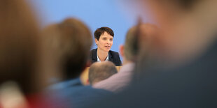 Frauke Petry hinter verschwommenen Silhouetten