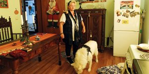 Eine Frau steht neben einem weißen Hund in einem Wohnzimmer