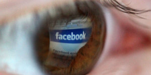1A-Symbolbild eines Auges, in dessen Iris sich das Facebook-Logo spiegelt