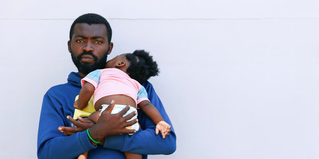 Ein Flüchtling hält ein kleines Mädchen auf dem Arm