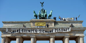 Aktivisten der „Identitären Bewegung“ stehen auf dem Brandenburger Tor und haben ein Banner mit der Aufschrift „Sichere Grenzen – Sichere Zukunft“ aufgehängt“