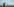Ein sommerliches Feld, blauer Himmel. Ein Mann hält ein kleines weißes Flugzeug mit beiden Händen über seinen Kopf