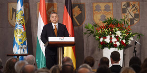 Viktor Orbán hinter einem Stehpult vor Fahnen