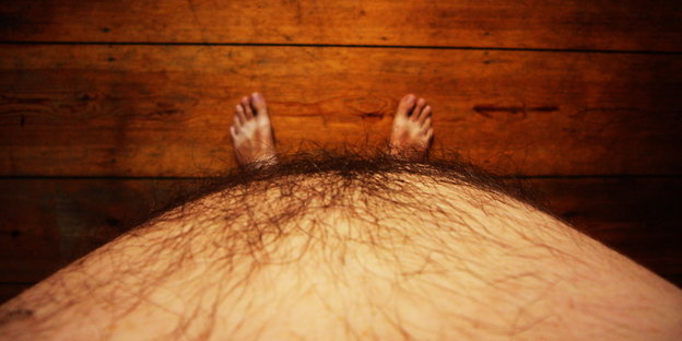 Ein von oben fotografierter dicker Männerbauch, unten sieht man die Füße