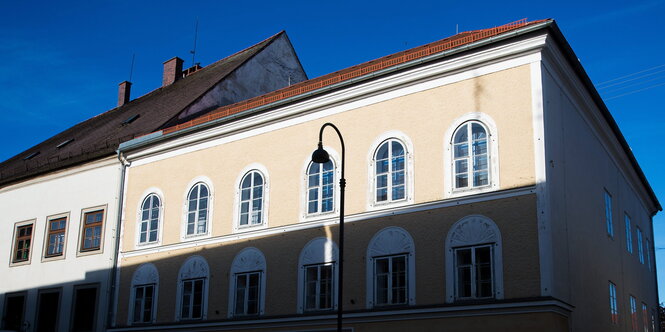 beiges Haus, bei dem die Sonne das obere Stockwerk anleuchtet, der Rest liegt im Schatten