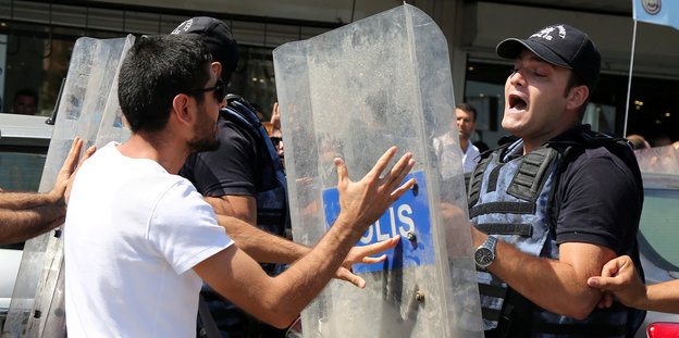 Ein Demonstrant und ein Polizist mit Schutzschild gehen aufeinander los