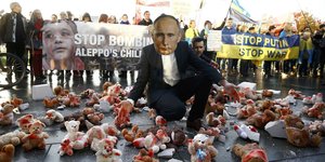 Demonstranten mit Putinmaske und blutigen Plüschteddybären