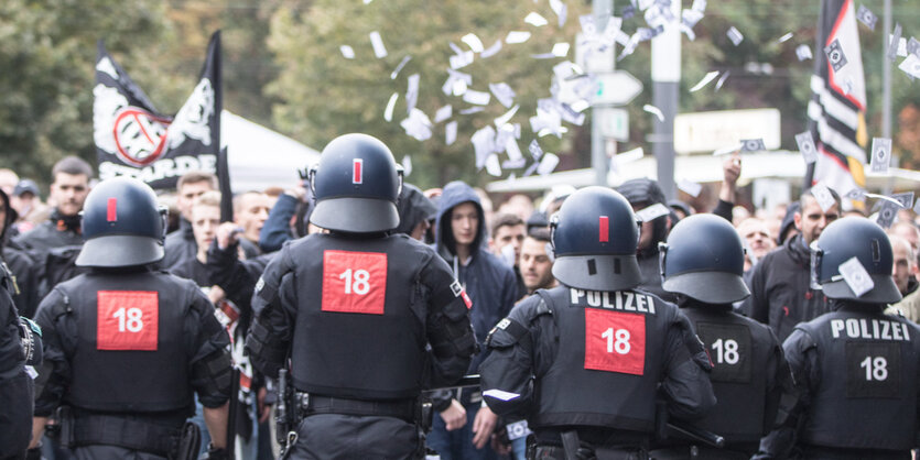 Im Vordergrund Polizei, im Hintergrund eine Fan-Demo und durch die Luft fliegende Tickets