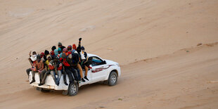 Migranten sitzen auf der Ladefläche eines Autos in Agadez