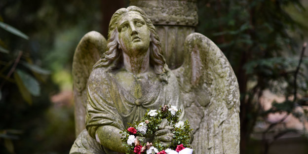 ein steinerner Engel mit Blumenkranz
