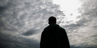 Silhouette eines Mannes vor wolkenverhangenem Himmel