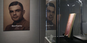 Ein Portrait von Alan Turing hängt im Museum, daneben in einer Vitrine steht sein Notitzbuch