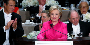 Hillary Clinton am Rednerpult, hinter ihr applaudieren die Umsitzenden